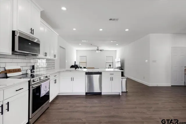 a kitchen with a sink wooden floor and stainless steel appliances