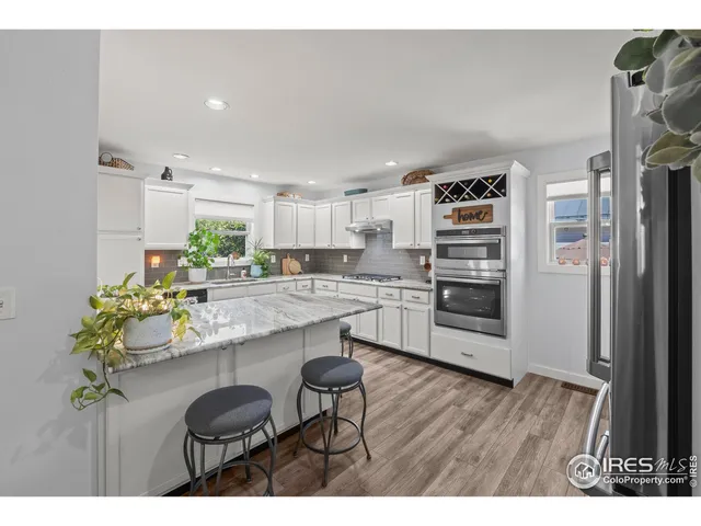 a kitchen with stainless steel appliances a kitchen island hardwood floor sink and stove