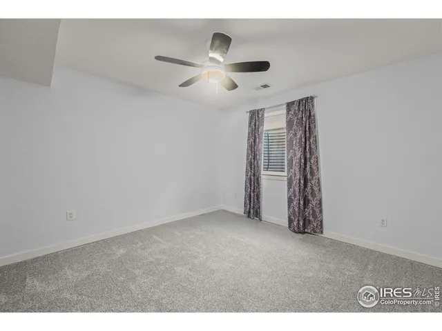 a view of an empty room with chandelier fan