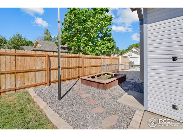 a view of a backyard with table and chairs under an umbrella with potted plants