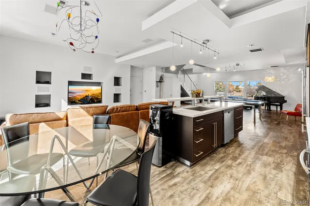 a living room with stainless steel appliances kitchen island granite countertop furniture a fireplace a rug and a chandelier