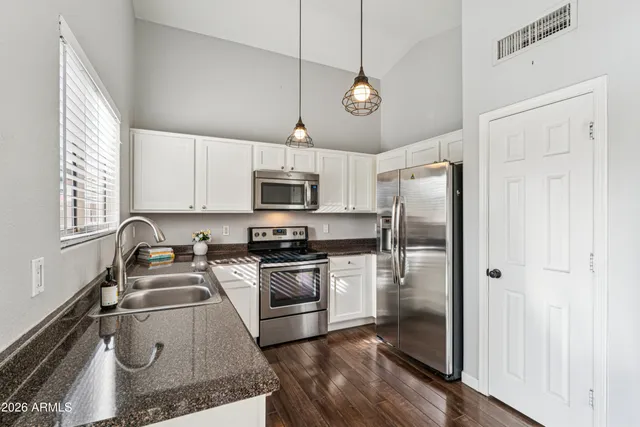a kitchen with stainless steel appliances granite countertop a sink a stove a refrigerator cabinets and a window