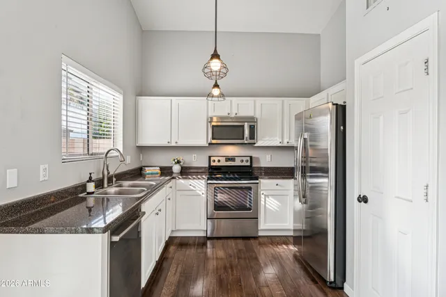 a kitchen with stainless steel appliances granite countertop a sink a stove a refrigerator and cabinets