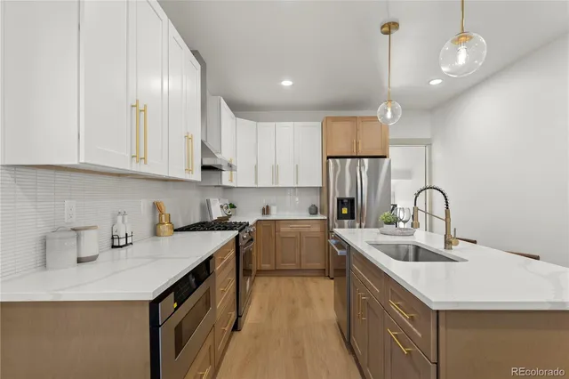 a kitchen with a sink dishwasher a stove top oven a refrigerator with wooden cabinets and floor