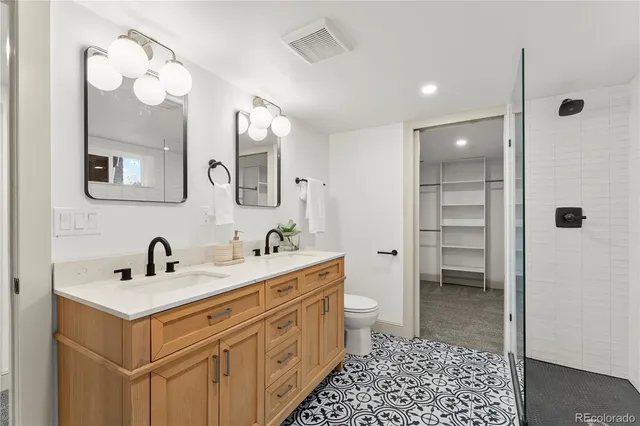 a bathroom with a double vanity sink mirror and toilet