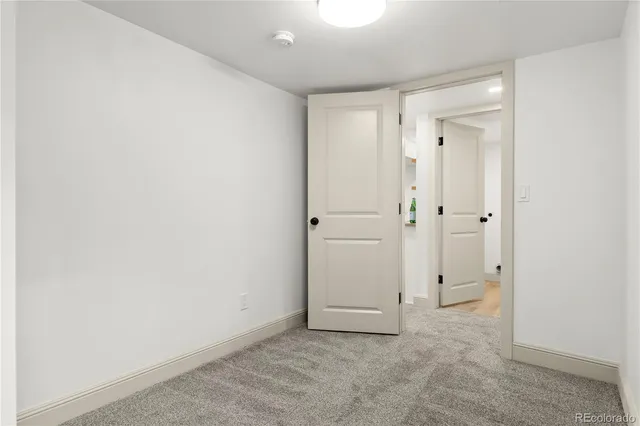 an empty room with white cabinet and mirror