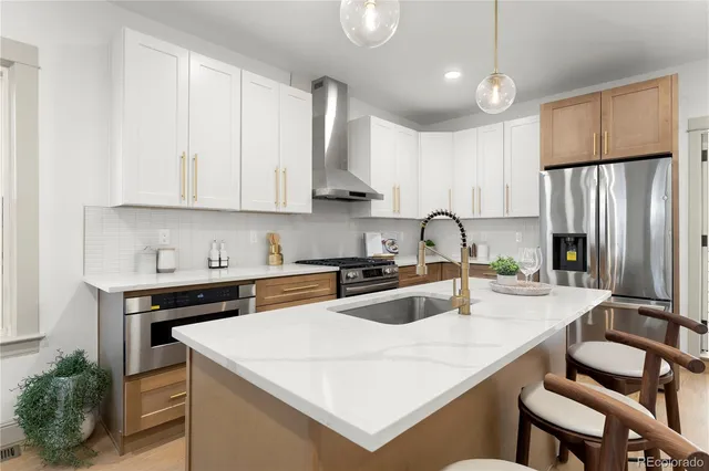 a kitchen with a sink a stove a refrigerator and white cabinets with wooden floor