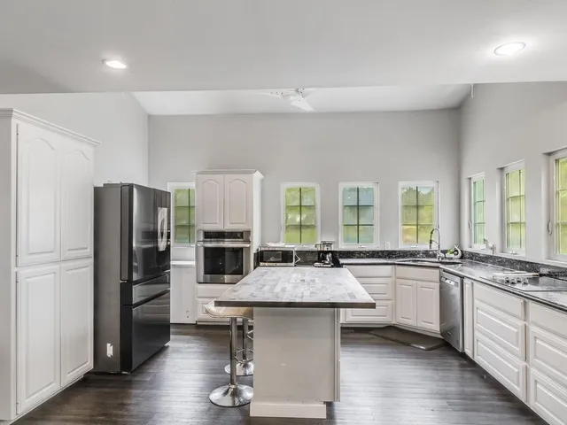 a kitchen with granite countertop stainless steel appliances a sink stove refrigerator and cabinets