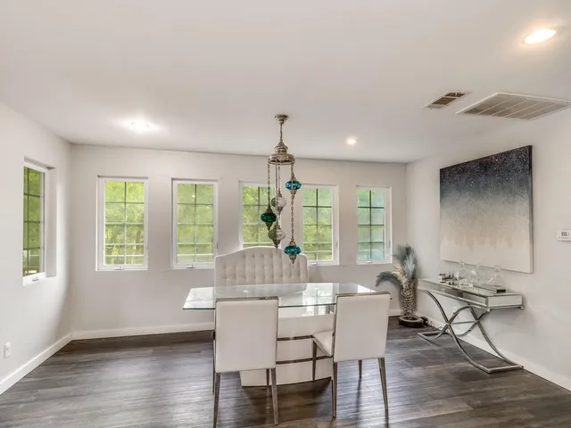 a dining room with wooden floor a chandelier a glass table and chairs