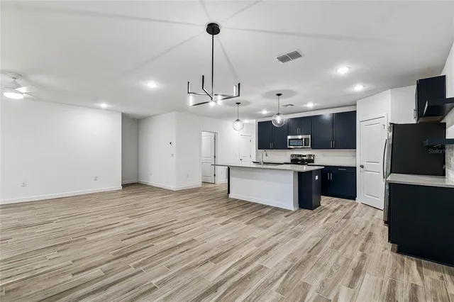 a large kitchen with a wooden floor and stainless steel appliances