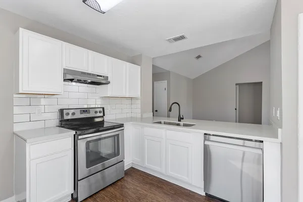 a kitchen with stainless steel appliances granite countertop a sink stove and white cabinets