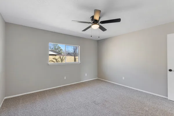 an empty room with a window and a fan