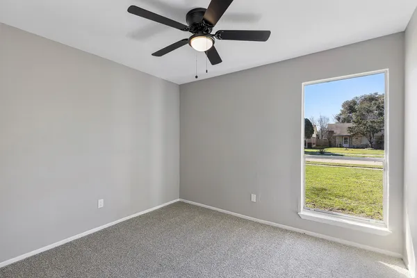an empty room with a window and a ceiling fan