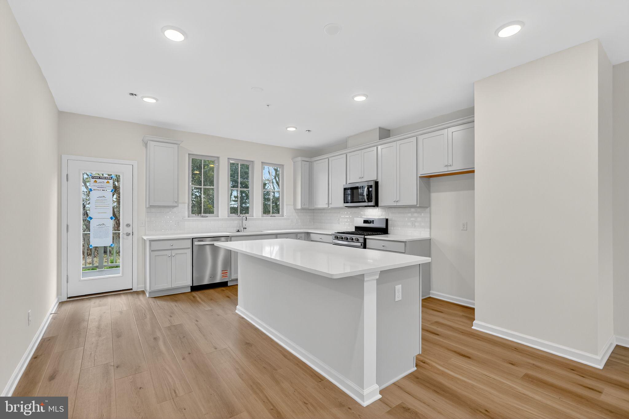 103 Beacon Court, Unit 10102 Lansdale, PA 19446 - Photo 12 of 17 a kitchen with stainless steel appliances a sink a stove a refrigerator cabinets and a wooden floor