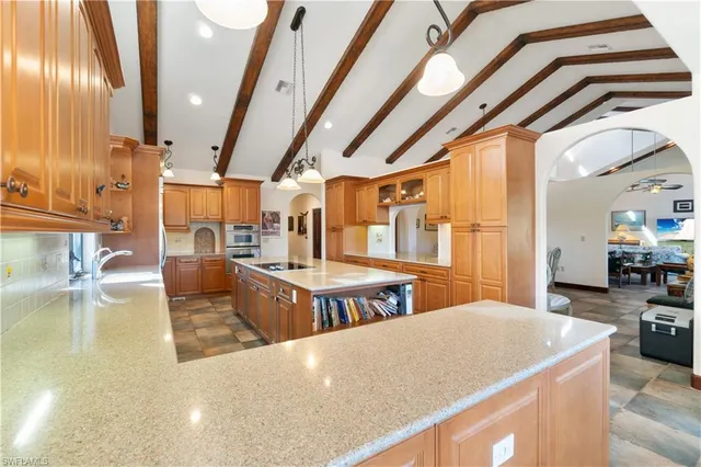 a dining hall with stainless steel appliances kitchen island granite countertop a table chairs and couches