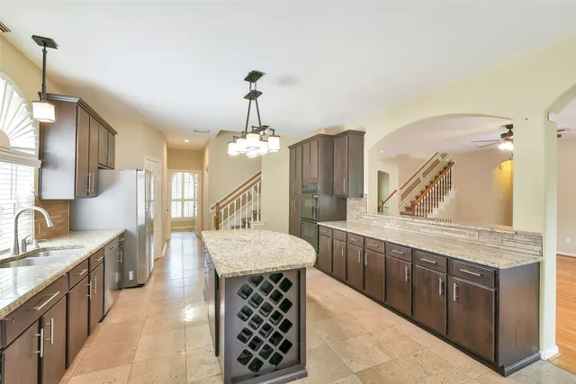 a large kitchen with kitchen island a sink stainless steel appliances and a chandelier