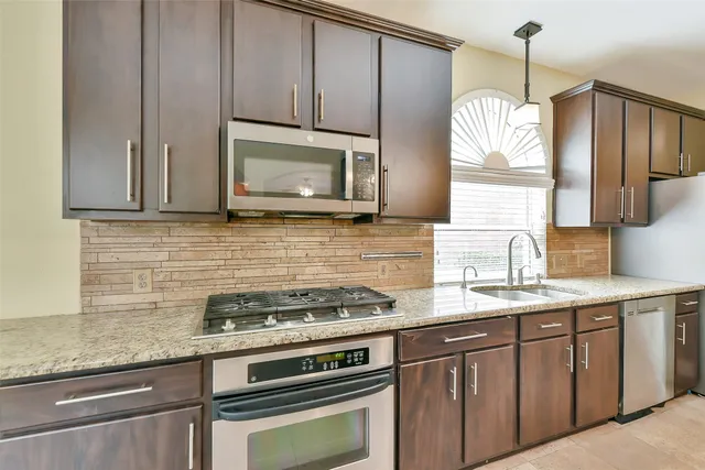 a kitchen with cabinets wooden floor and stainless steel appliances