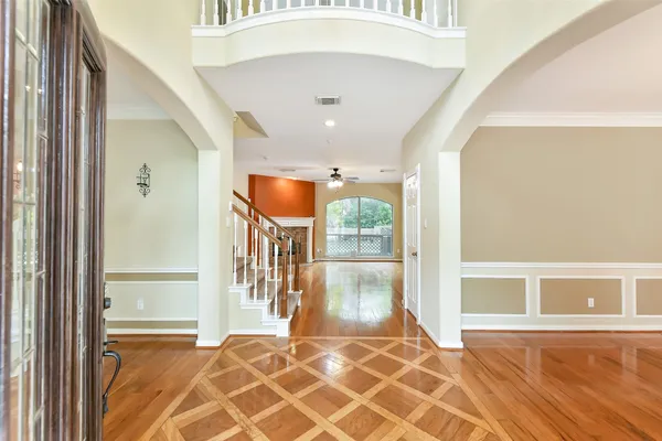 a view of empty room with wooden floor and fan