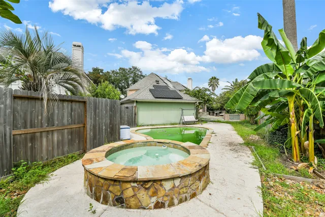 a view of a backyard with a fountain plants and large tree