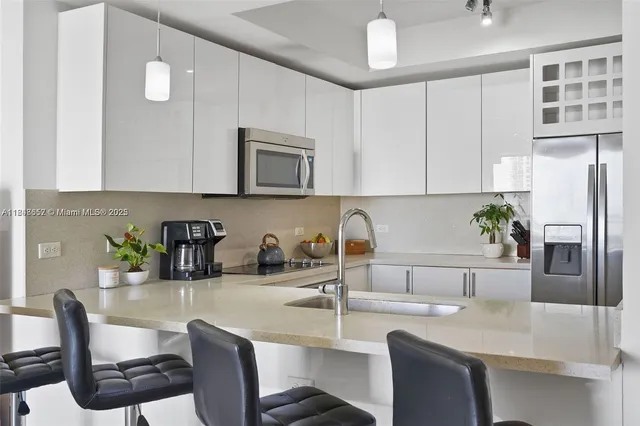 a kitchen with stainless steel appliances granite countertop a sink a stove a microwave a refrigerator a counter space and cabinets