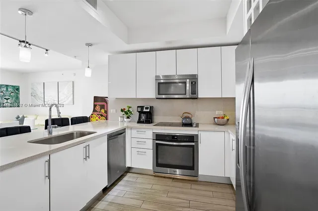 a kitchen with a sink white cabinets and stainless steel appliances