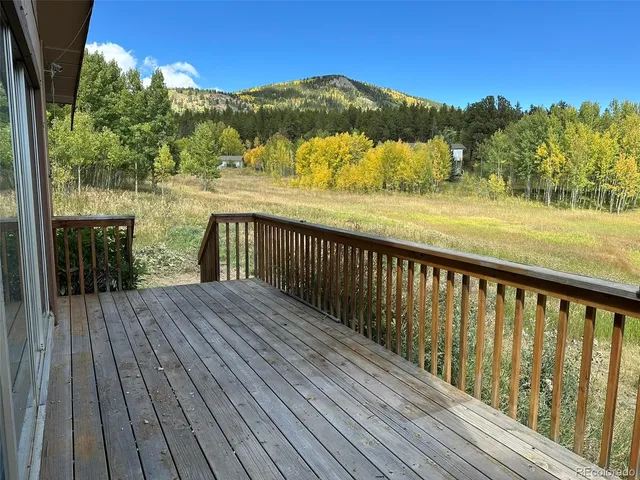 a balcony with wooden floor and yard in the back