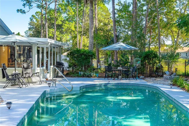 a view of a swimming pool with a patio and trees in the background