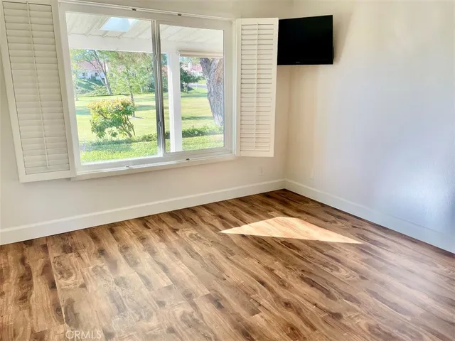 a view of empty room with wooden floor and fan