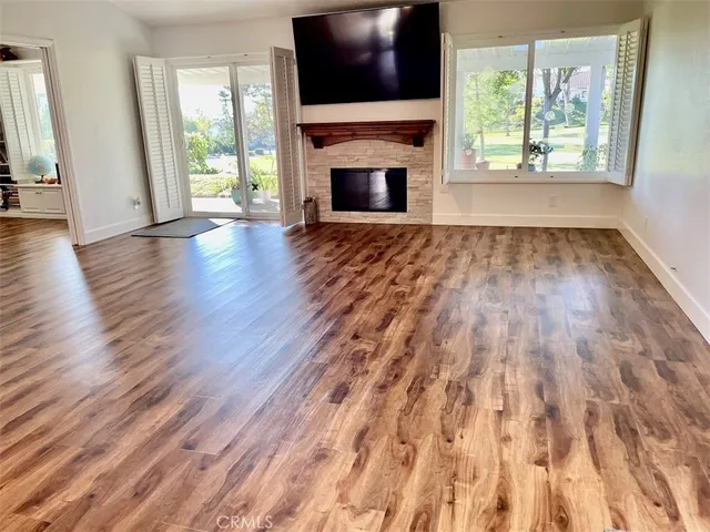 a view of empty room with wooden floor and fireplace