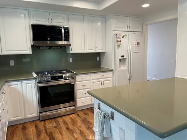 a kitchen with stainless steel appliances a stove a microwave and white cabinets