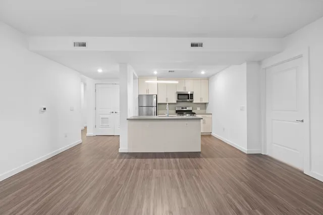 a large kitchen with wooden floor and stainless steel appliances