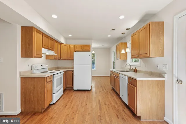 a kitchen with a sink a refrigerator a stove top oven a counter space and wooden floor