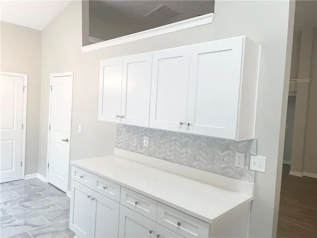 an empty room with wooden floor fireplace and windows