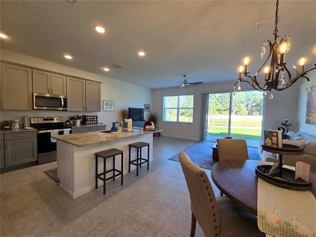 a kitchen with stainless steel appliances granite countertop a stove a sink dishwasher a dining table and chairs with wooden floor