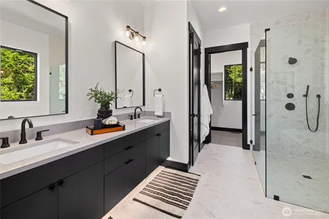 a spacious bathroom with a double vanity sink a large mirror and shower