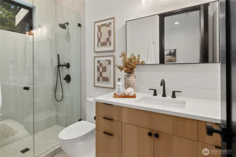 a bathroom with a granite countertop sink toilet a mirror a vanity and shower