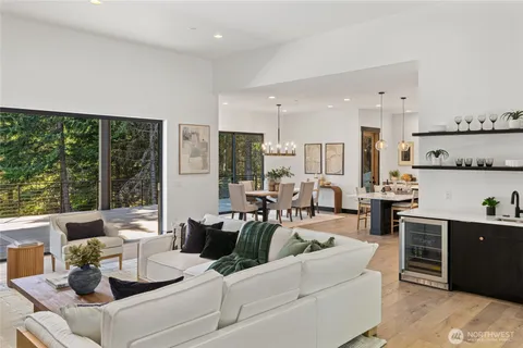 a living room with furniture large windows and wooden floor