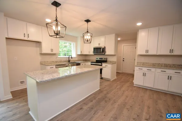 a kitchen with kitchen island granite countertop a sink a counter space appliances and cabinets