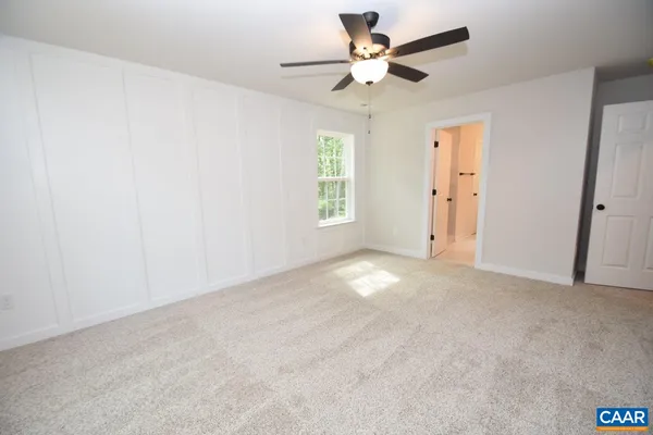 an empty room with windows and fan