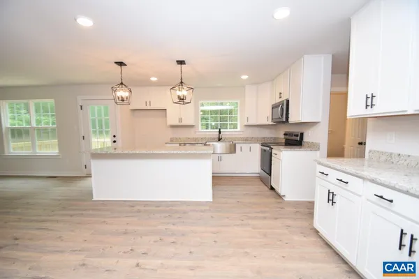 a large kitchen with kitchen island a stove a sink a center island and wooden floor