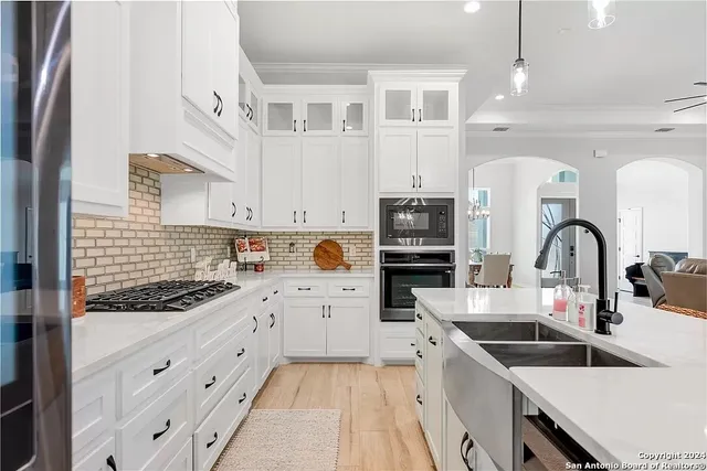 a kitchen with granite countertop a sink stainless steel appliances and white cabinets