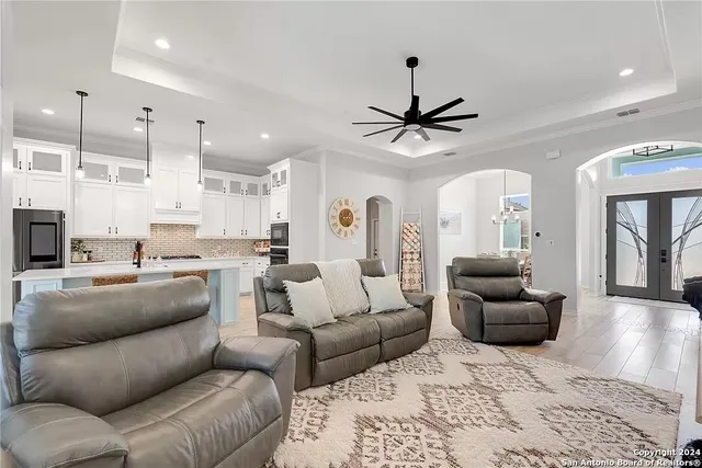 a living room with furniture kitchen view and a chandelier
