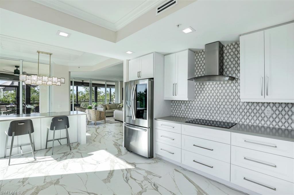 425 Cove Tower Drive, Unit 301 Naples, FL 34110 - Photo 13 of 43 a kitchen with granite countertop cabinets and chairs