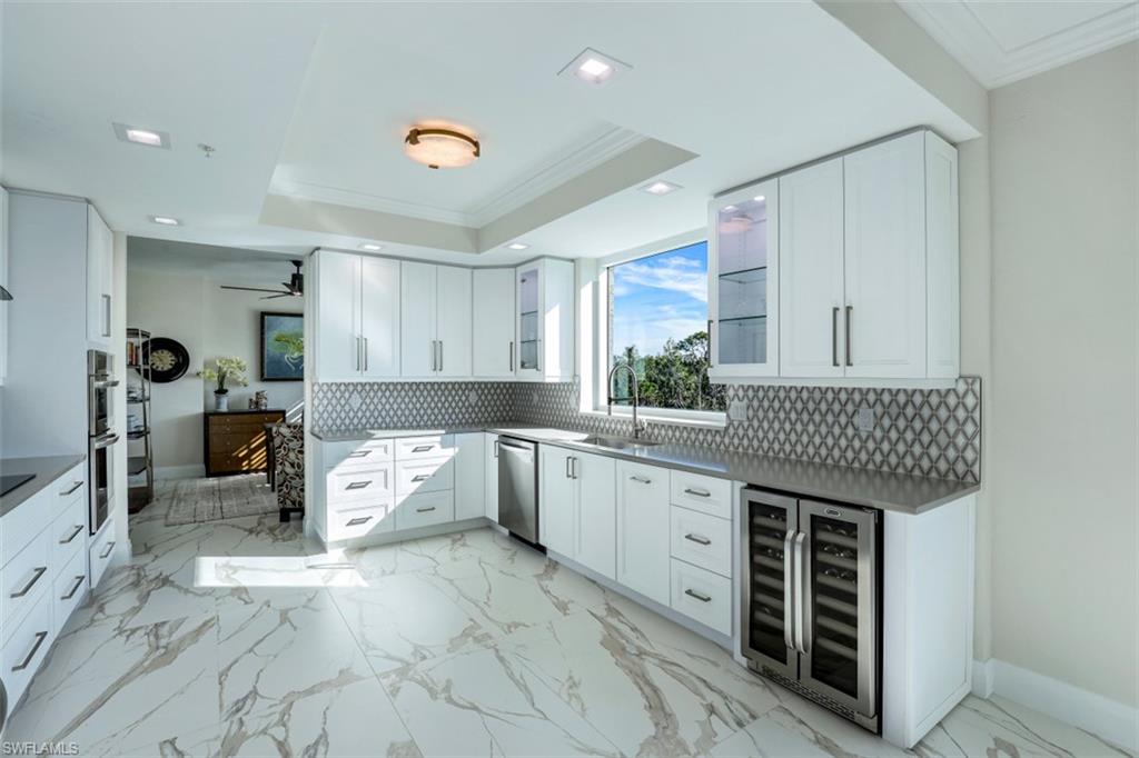 425 Cove Tower Drive, Unit 301 Naples, FL 34110 - Photo 14 of 43 a kitchen that has a lot of cabinets in it and wooden floors