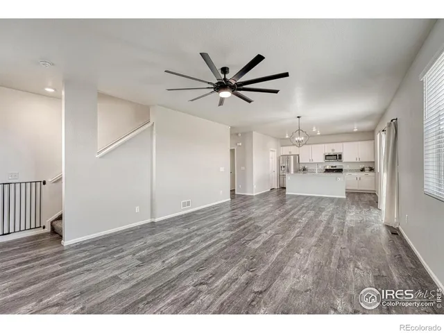 a view of a big room with wooden floor a ceiling fan and windows