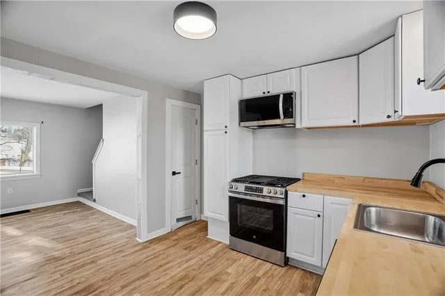 a kitchen with stainless steel appliances granite countertop a stove a sink and a microwave