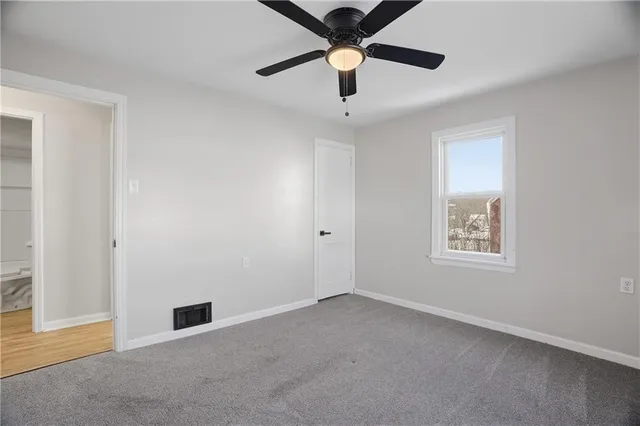 an empty room with ceiling fan and windows