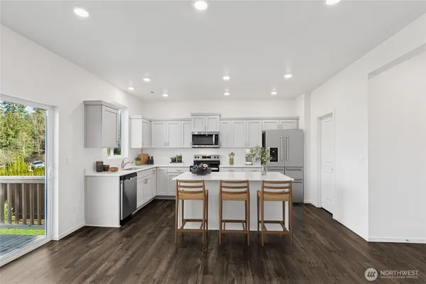 a kitchen with a sink a stove a refrigerator and white cabinets with wooden floor