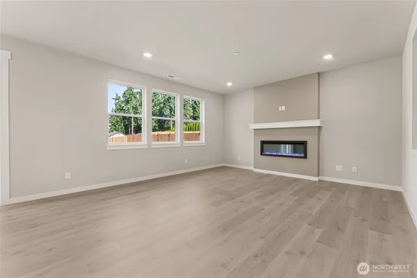 an empty room with windows and fireplace