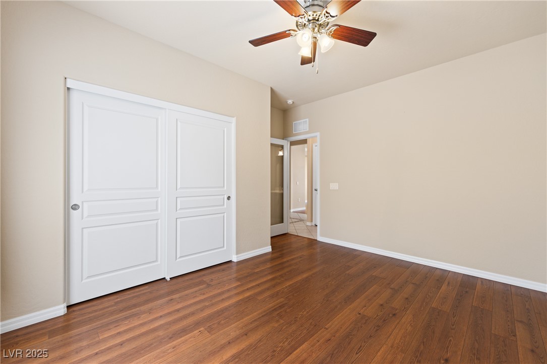 1551 Watchmans Point Mesquite, NV 89034 - Photo 13 of 62 Unfurnished bedroom featuring dark wood-type flooring, a ceiling fan, and a closet